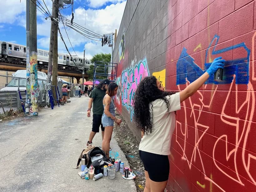Writers painting a wall in an alley